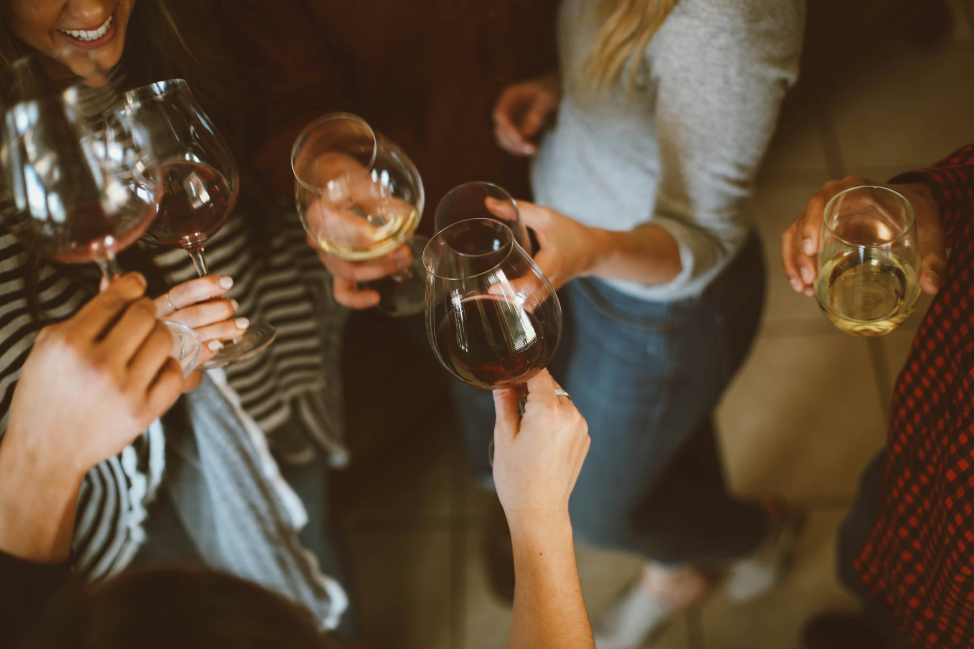 Gruppe Erwachsener stößt mit Wein- und Sektgläsern an.
